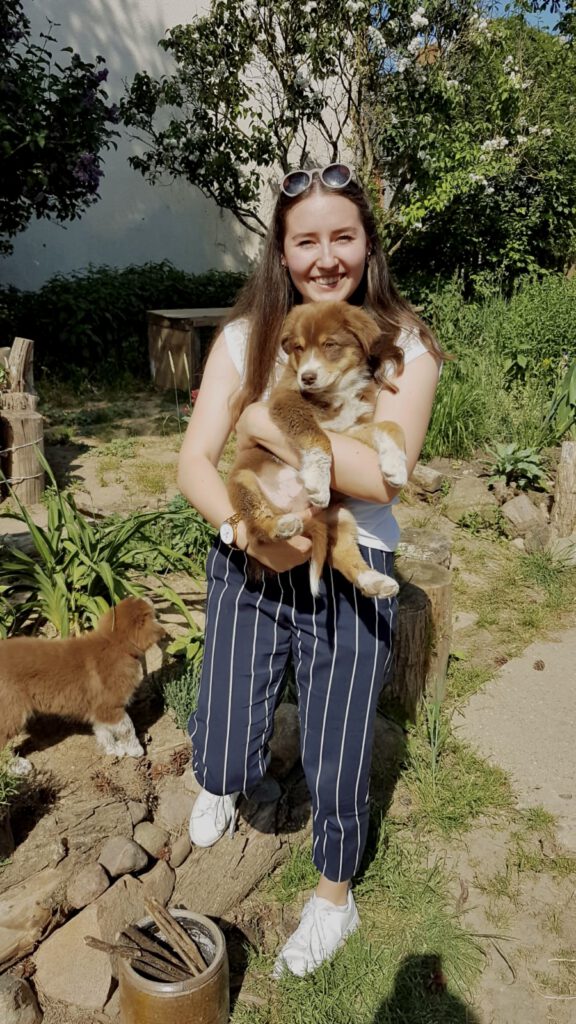 Nele hat Nemoo als Welpe auf dem Arm und lacht.